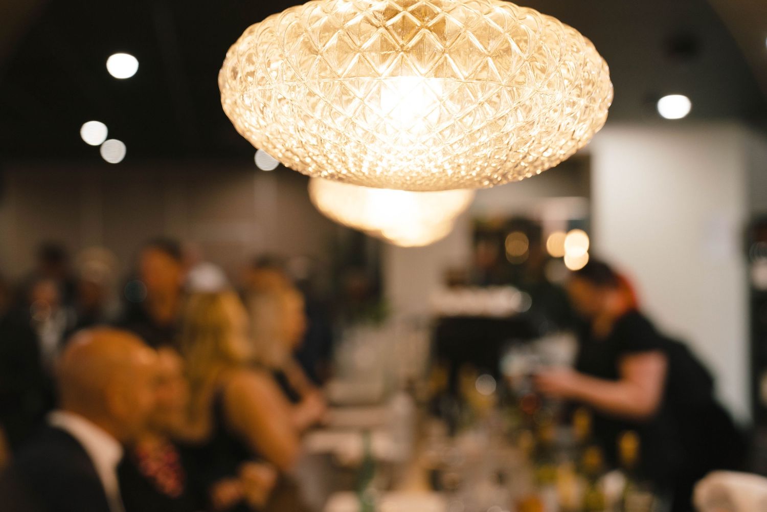 Elegant crystal chandelier illuminating a dimly lit event space.