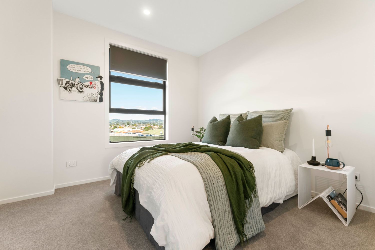 Modern bedroom interior with gray and white decor featuring green accent pillows and throw blanket.