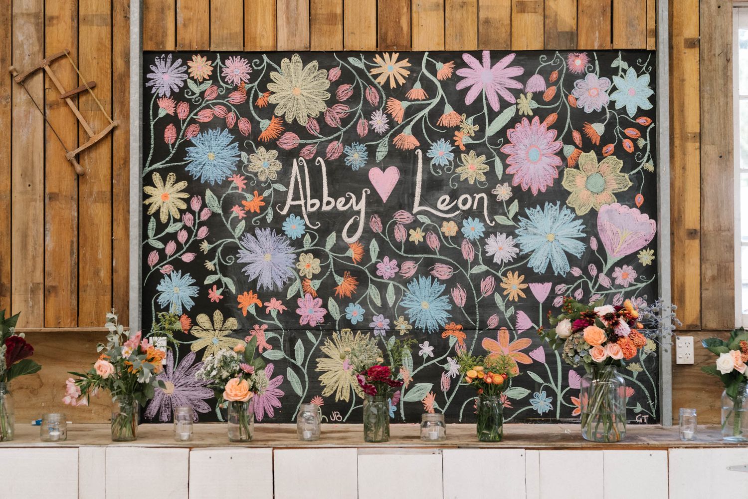 Rustic wooden storage cabinet with decorative floral pattern panels displays seasonal flowers and greenery arrangements.