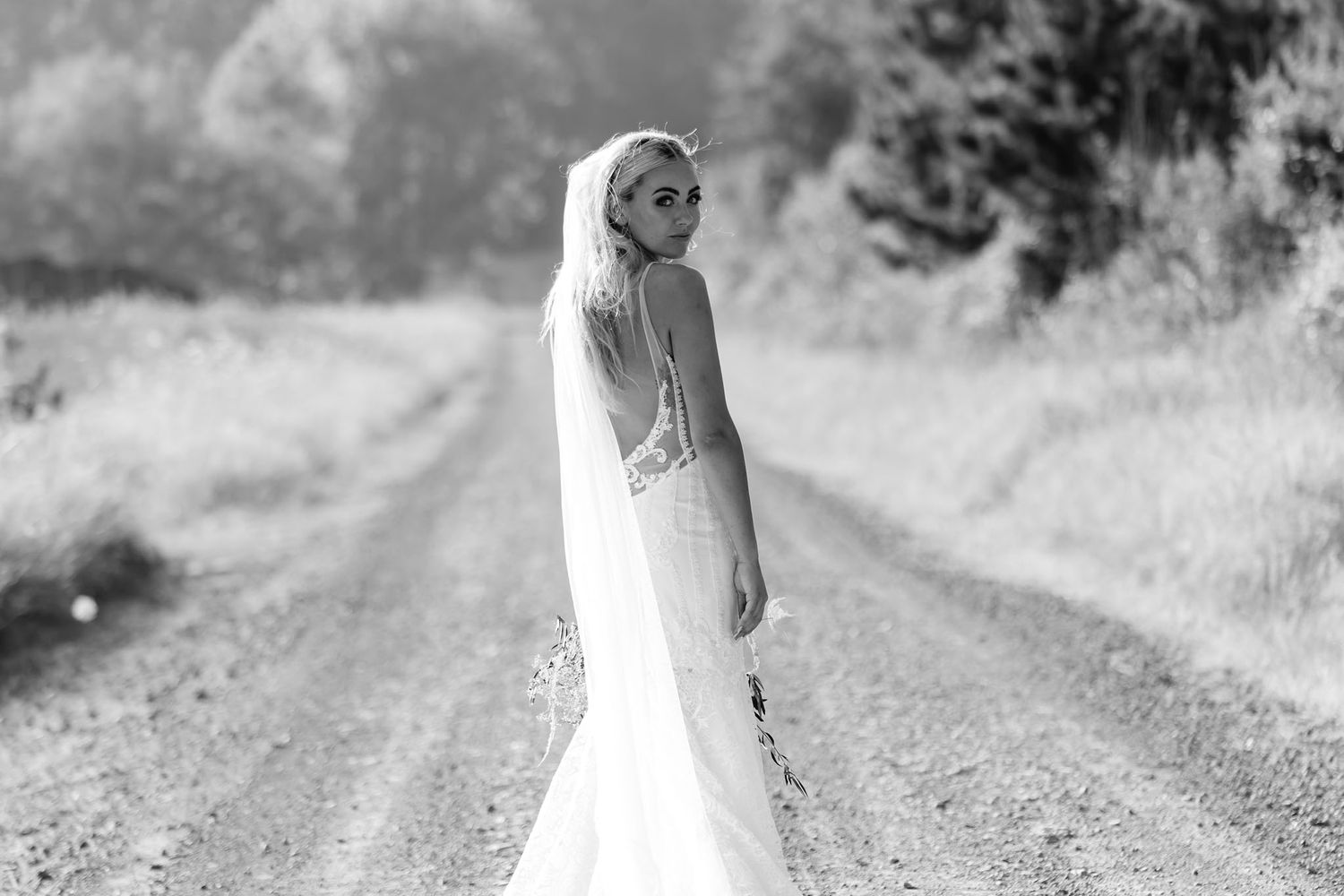 Black and white wedding photos show a couple walking hand in hand down a dirt path surrounded by nature.