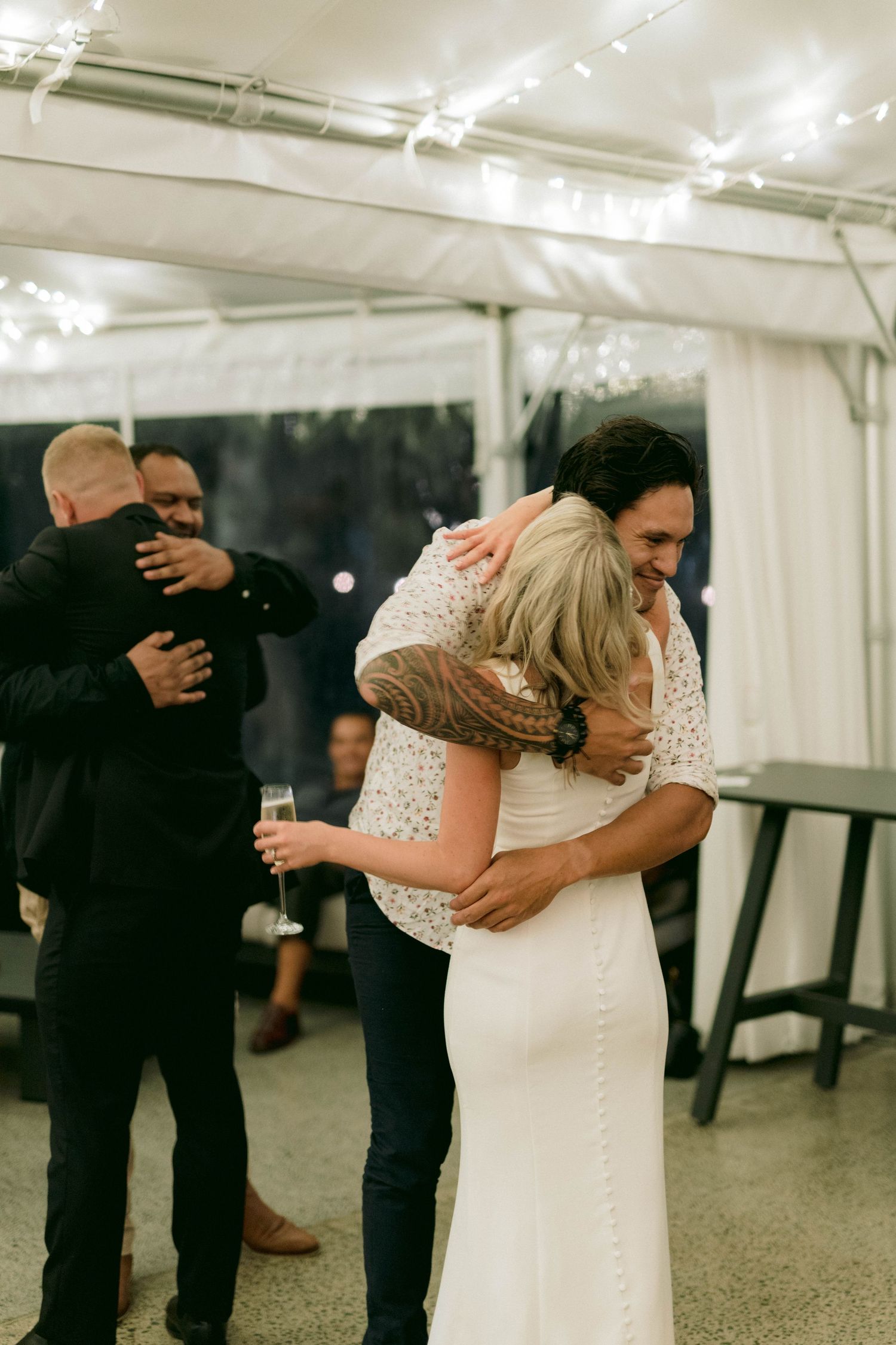 Wedding reception moments showing embraces and celebrations under a white tent.