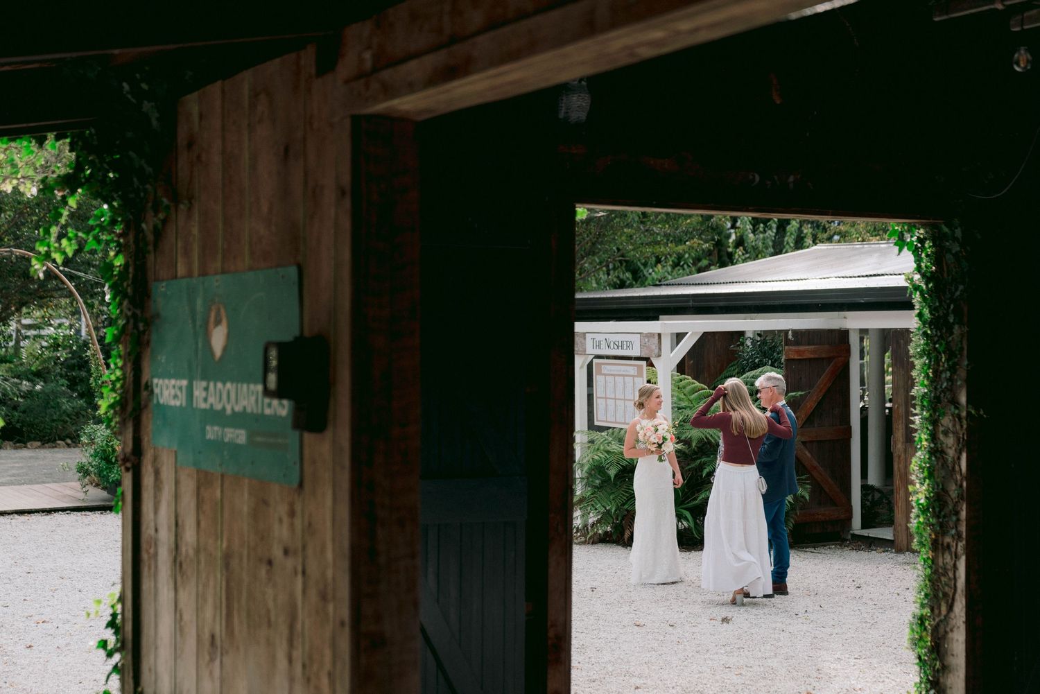 A rustic wooden entrance with signage frames dancing figures at an outdoor venue.