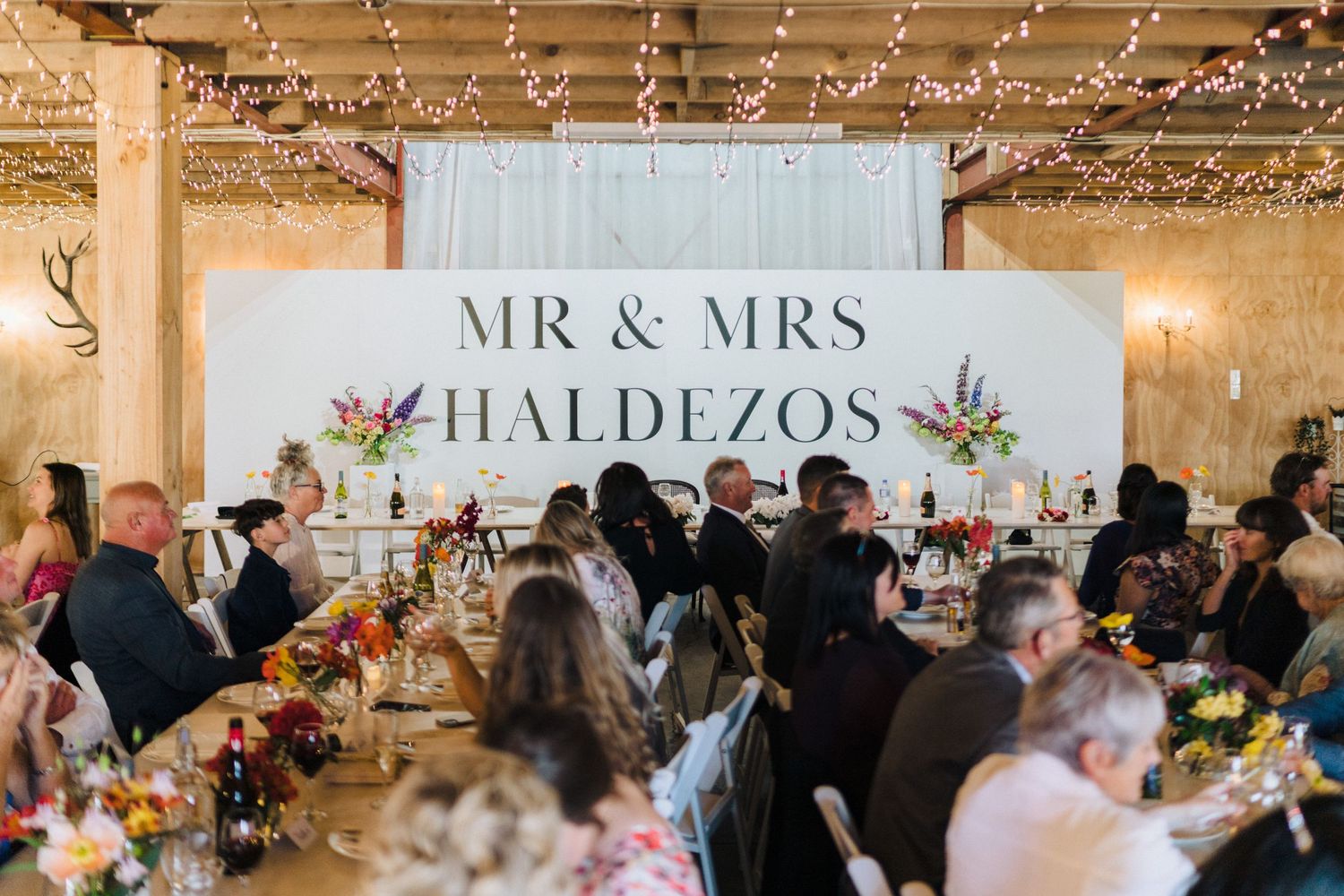 Wedding reception venue with Mr & Mrs Haldezos sign and string lights overhead.