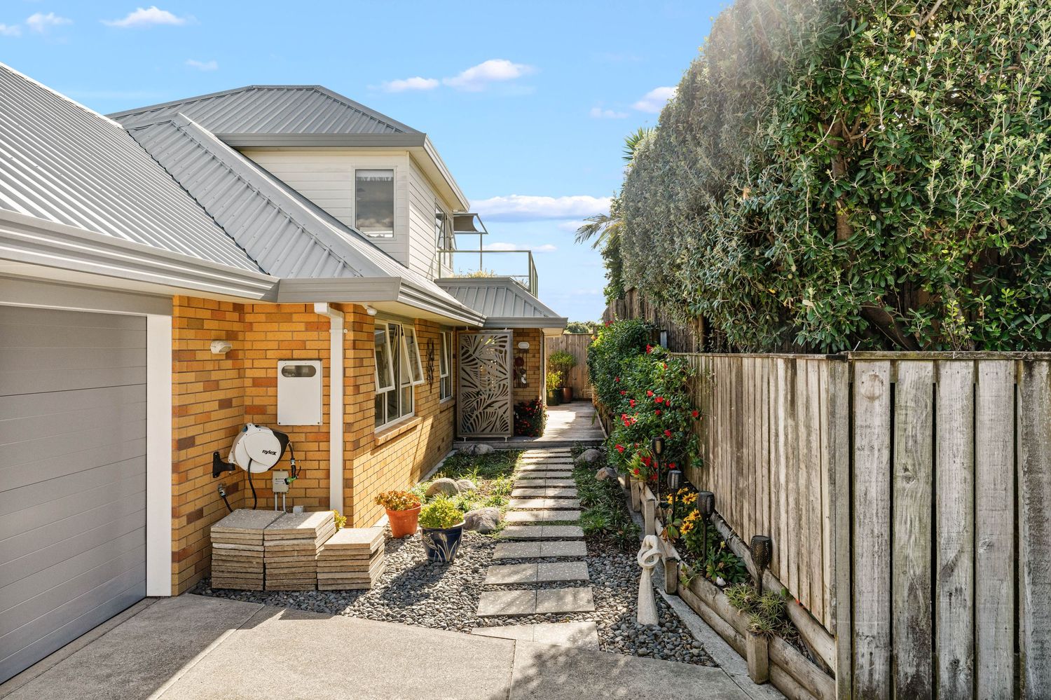 Exterior view of wooden fences along a narrow passageway with a mix of residential properties and natural foliage.