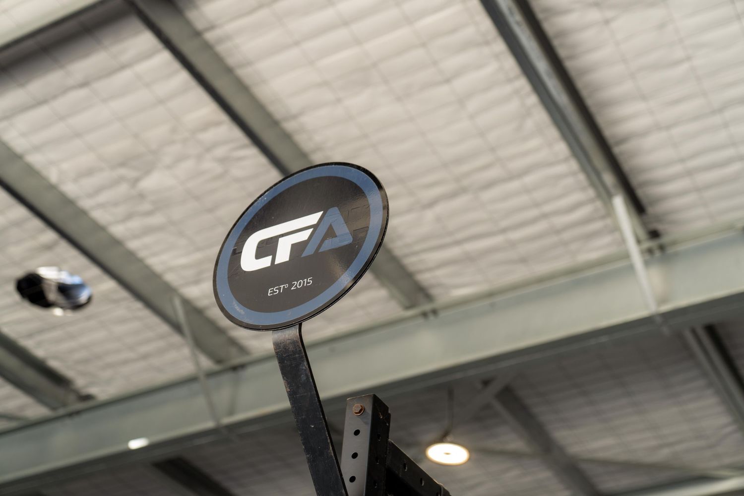Black and blue CrossFit timer mounted on a white industrial ceiling.