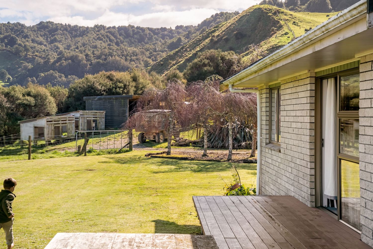 Long wooden deck with mountain views extends along a rustic countryside home.