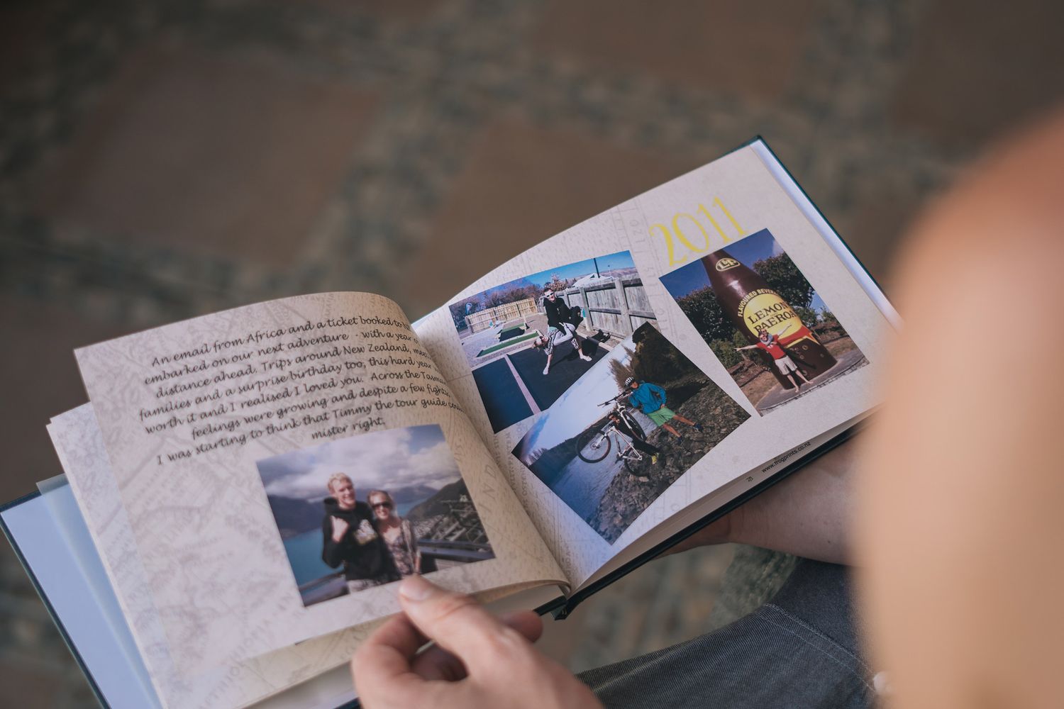 Several hands flip through pages of a photo album containing travel memories and family pictures.
