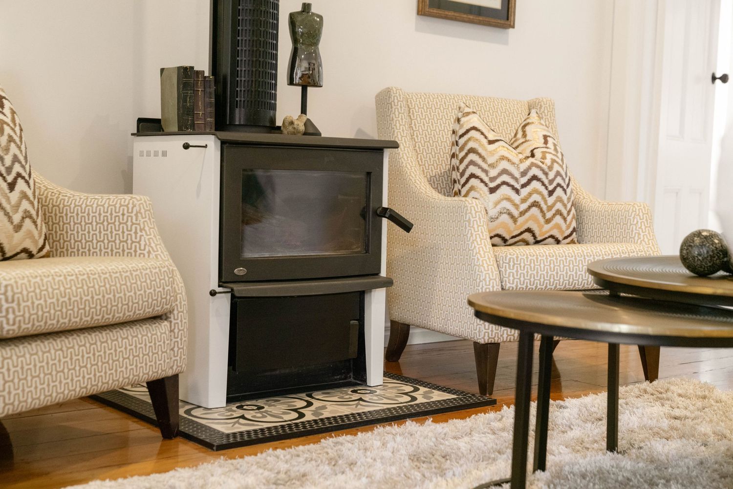 Cozy living room interior with wood stove and neutral furniture on area rug.