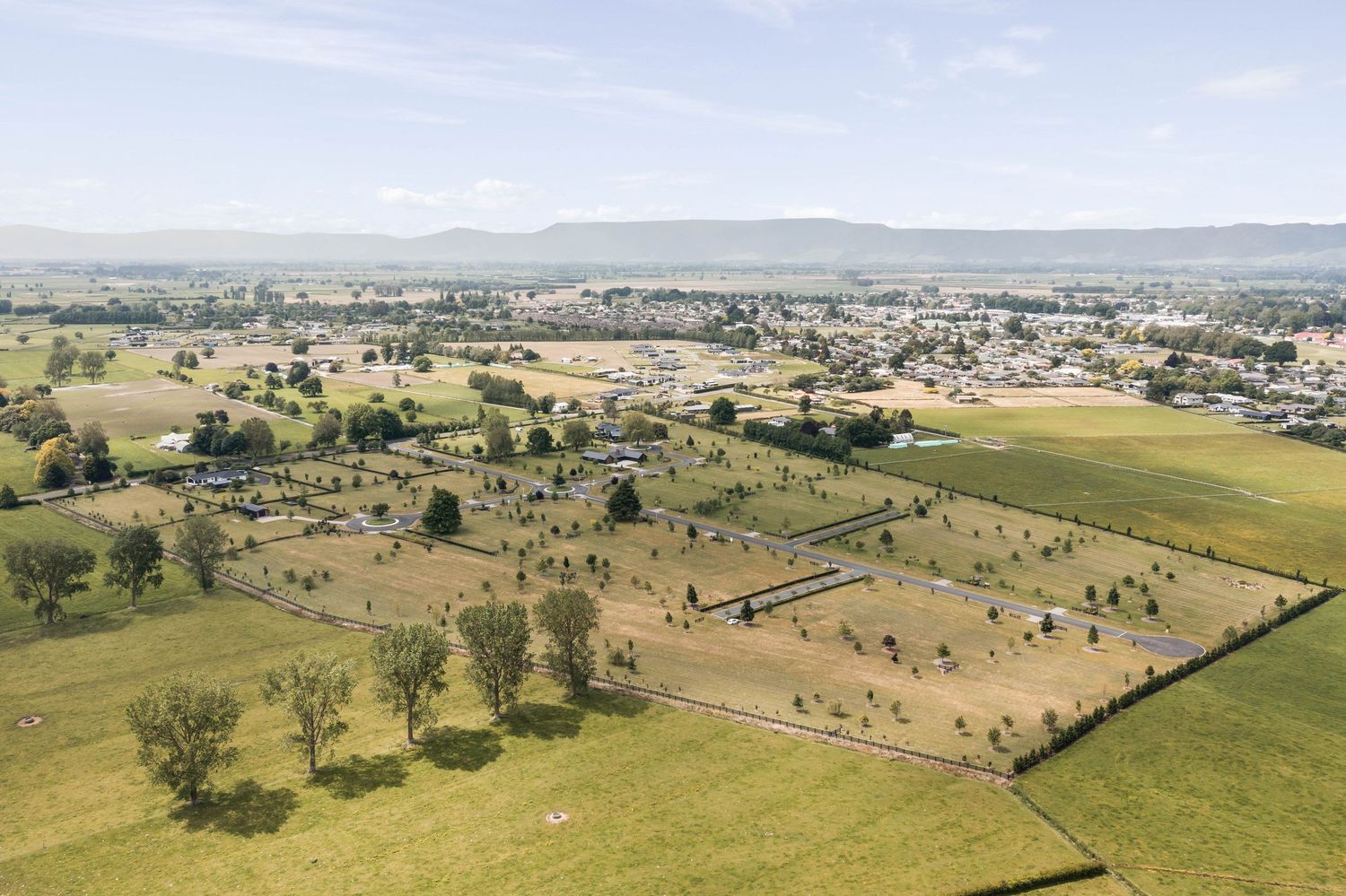 Aerial view of rural property development with scattered trees and rolling countryside landscape.