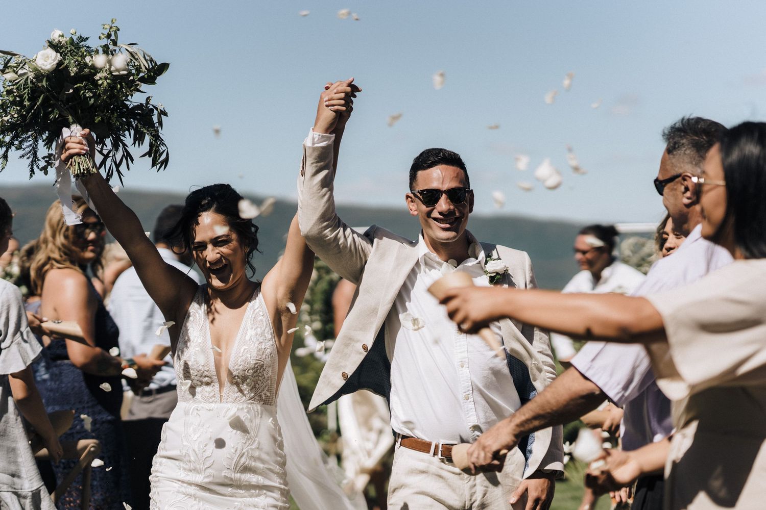 Wedding celebration with confetti toss outdoors as guests celebrate joyfully.