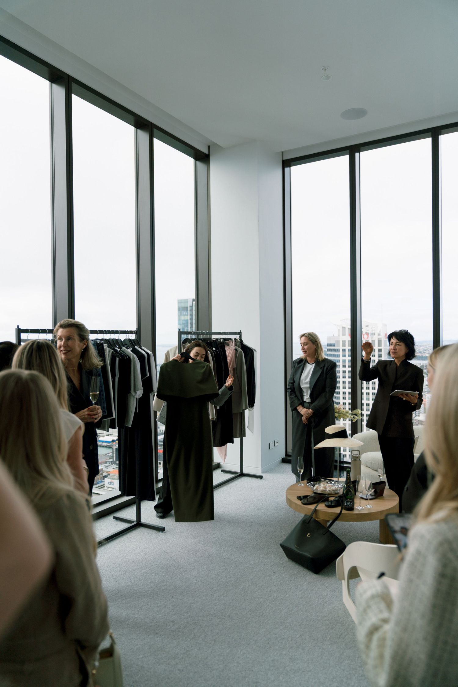Panoramic view of a modern retail showroom with floor-to-ceiling windows and black clothing displayed on racks.