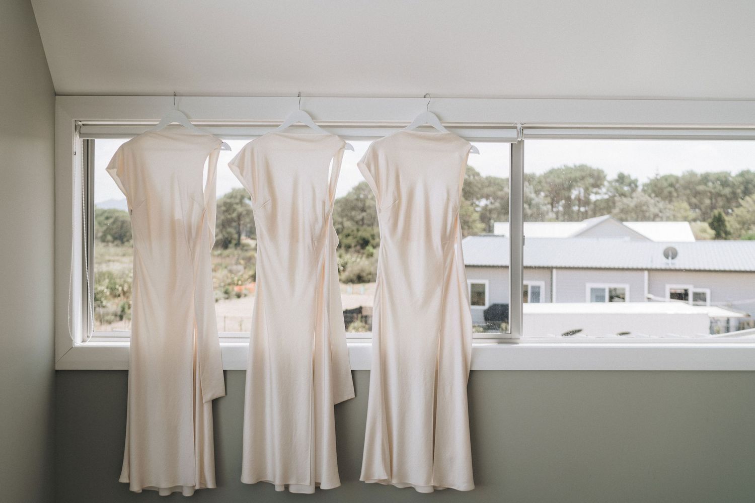 Natural light streams through windows into a white room with cream colored curtains and dark trim accents.