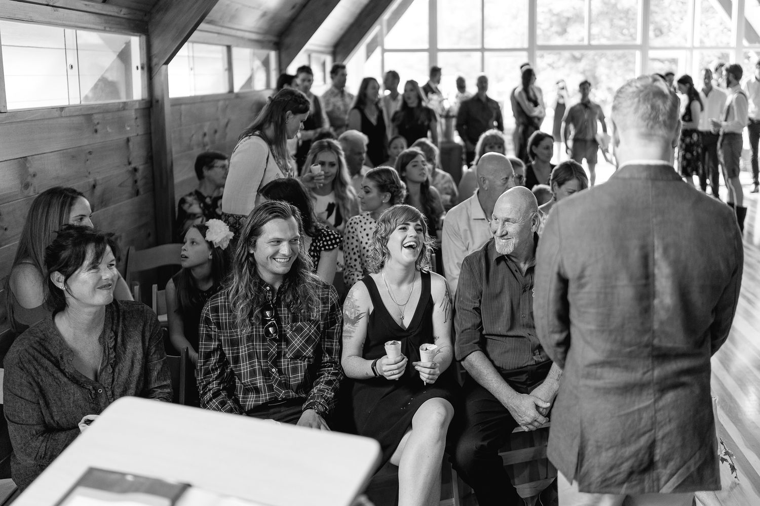 A crowd of people gathered indoors at a social event looking engaged in conversation and mingling.