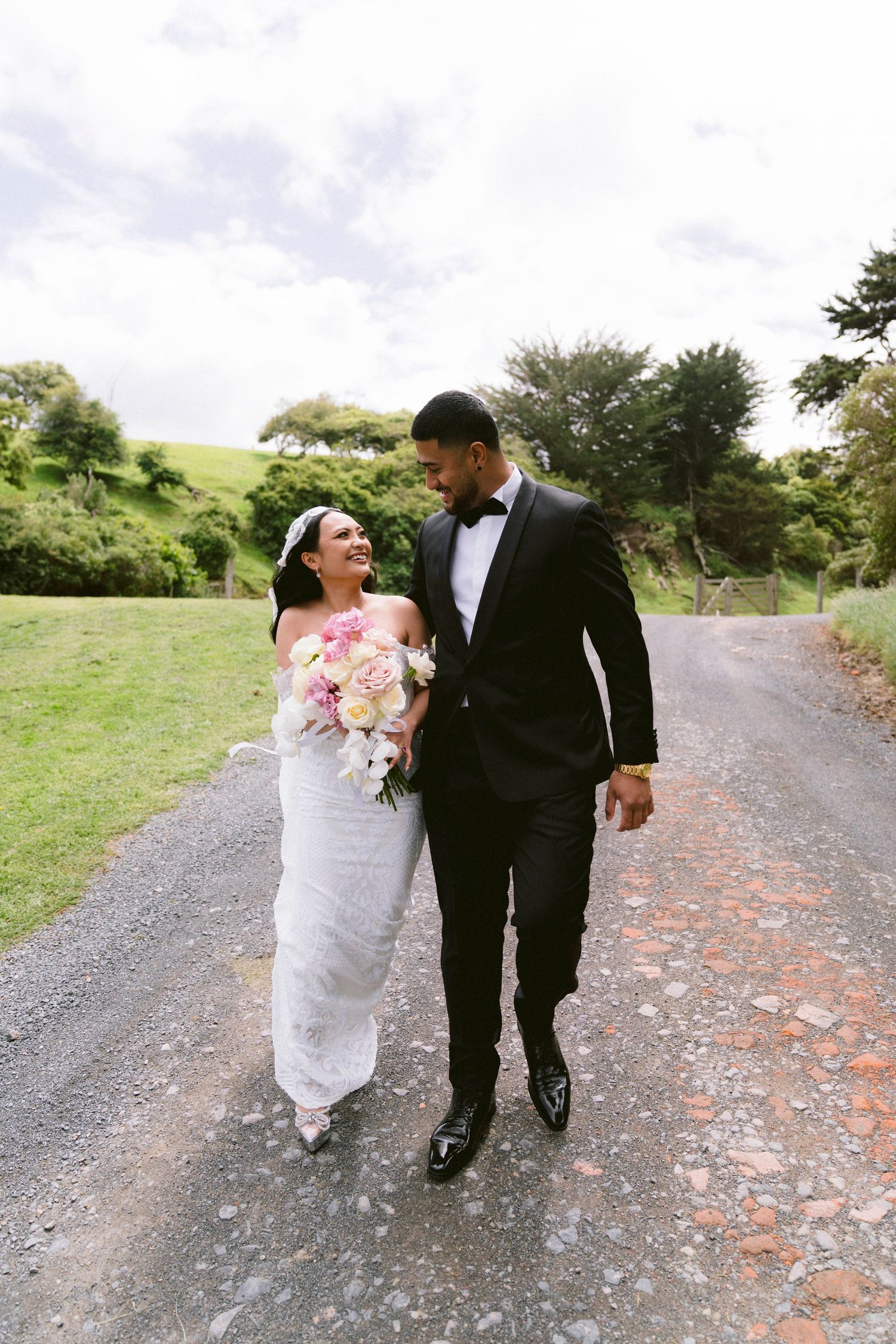 A couple walking along a country path surrounded by lush green hills during their wedding photo session.