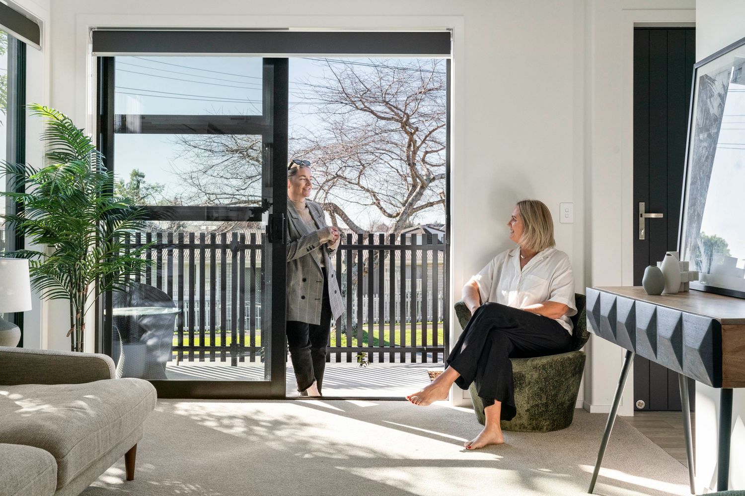 Two people relax in a modern living room with large windows overlooking a winter landscape.
