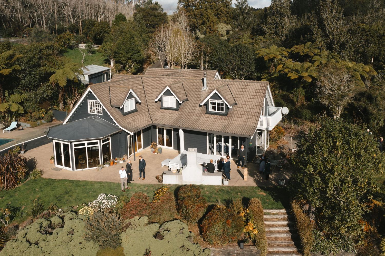 Aerial panorama of residential homes nestled among trees in a wooded hillside neighborhood with walkways.