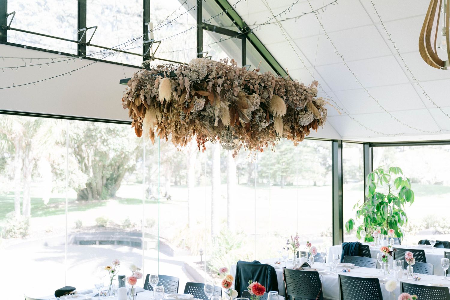 Wedding reception venue with rustic decor and hanging floral arrangements under a white tent canopy.