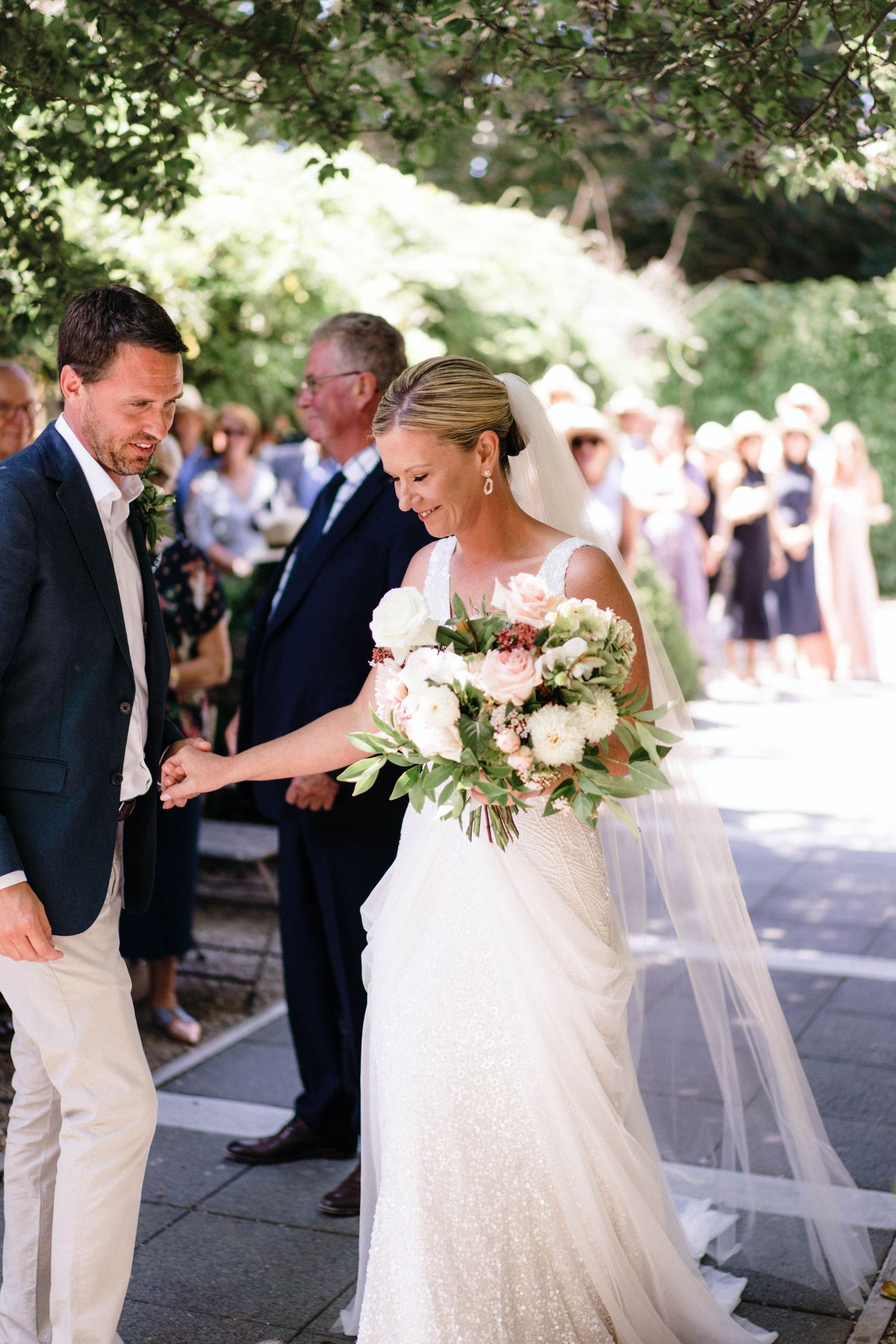 Wedding party members celebrate outdoors with elegant white and navy attire.