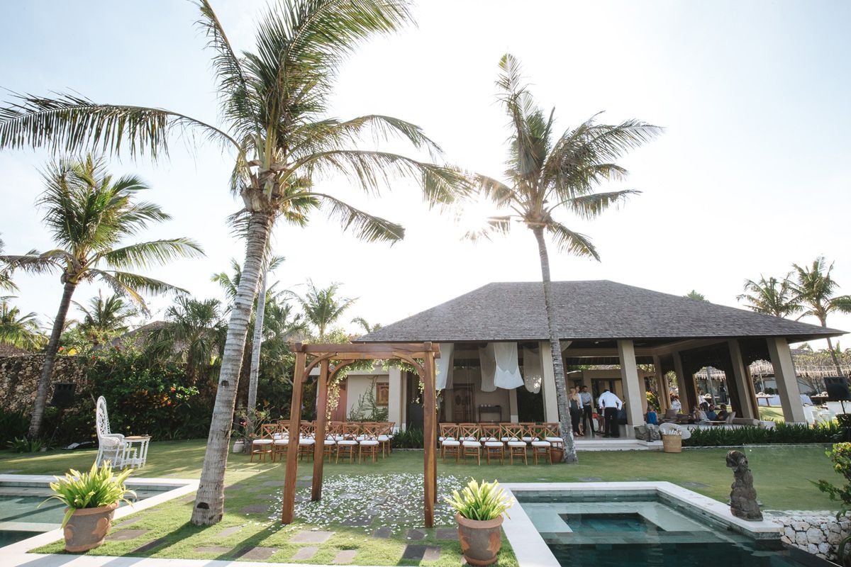 Palm trees and elegant outdoor seating areas line a beachfront resort property with pristine landscaping.