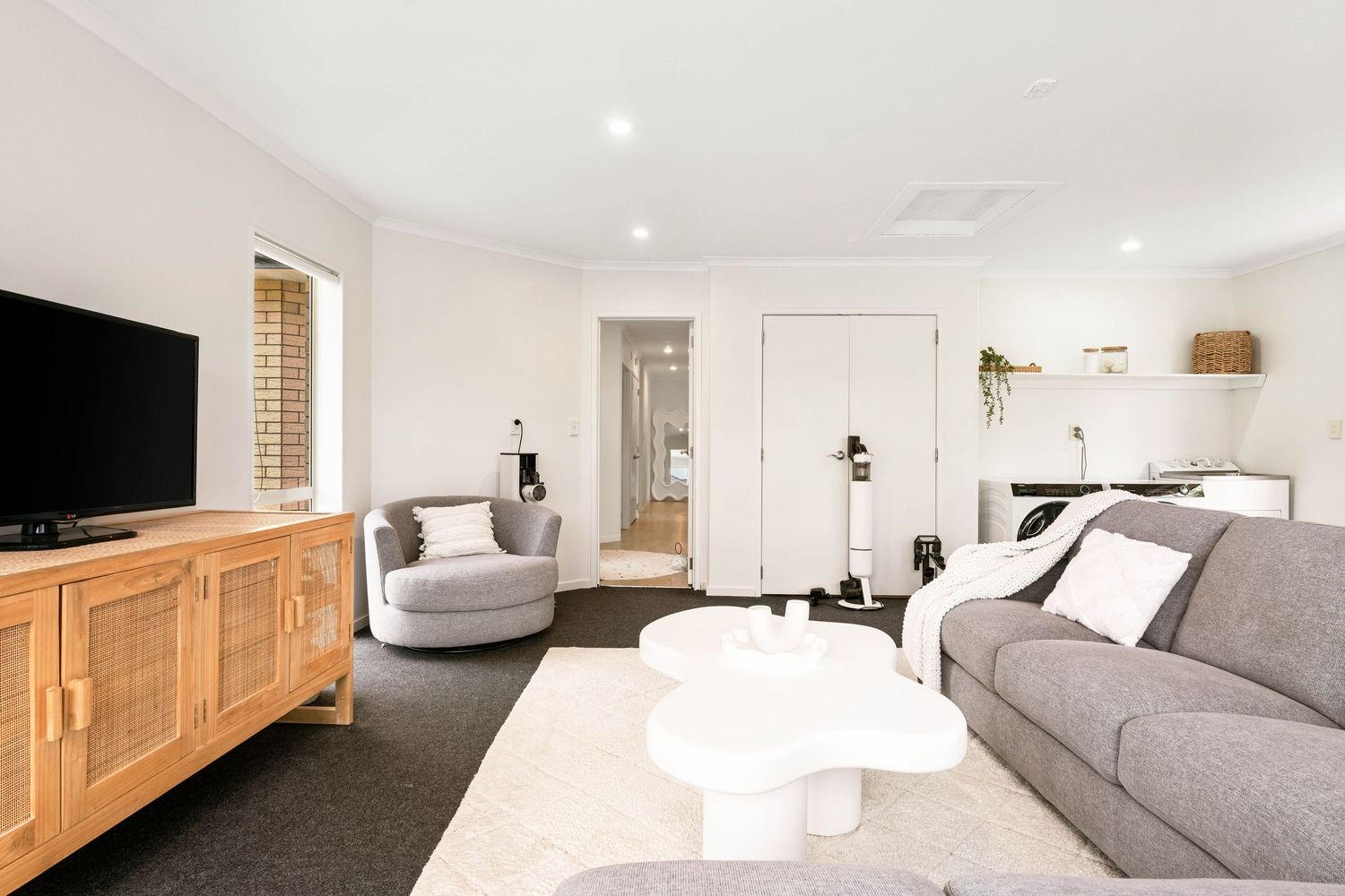 Modern basement family room with gray sectional couch, wooden media console, and hexagonal coffee table.
