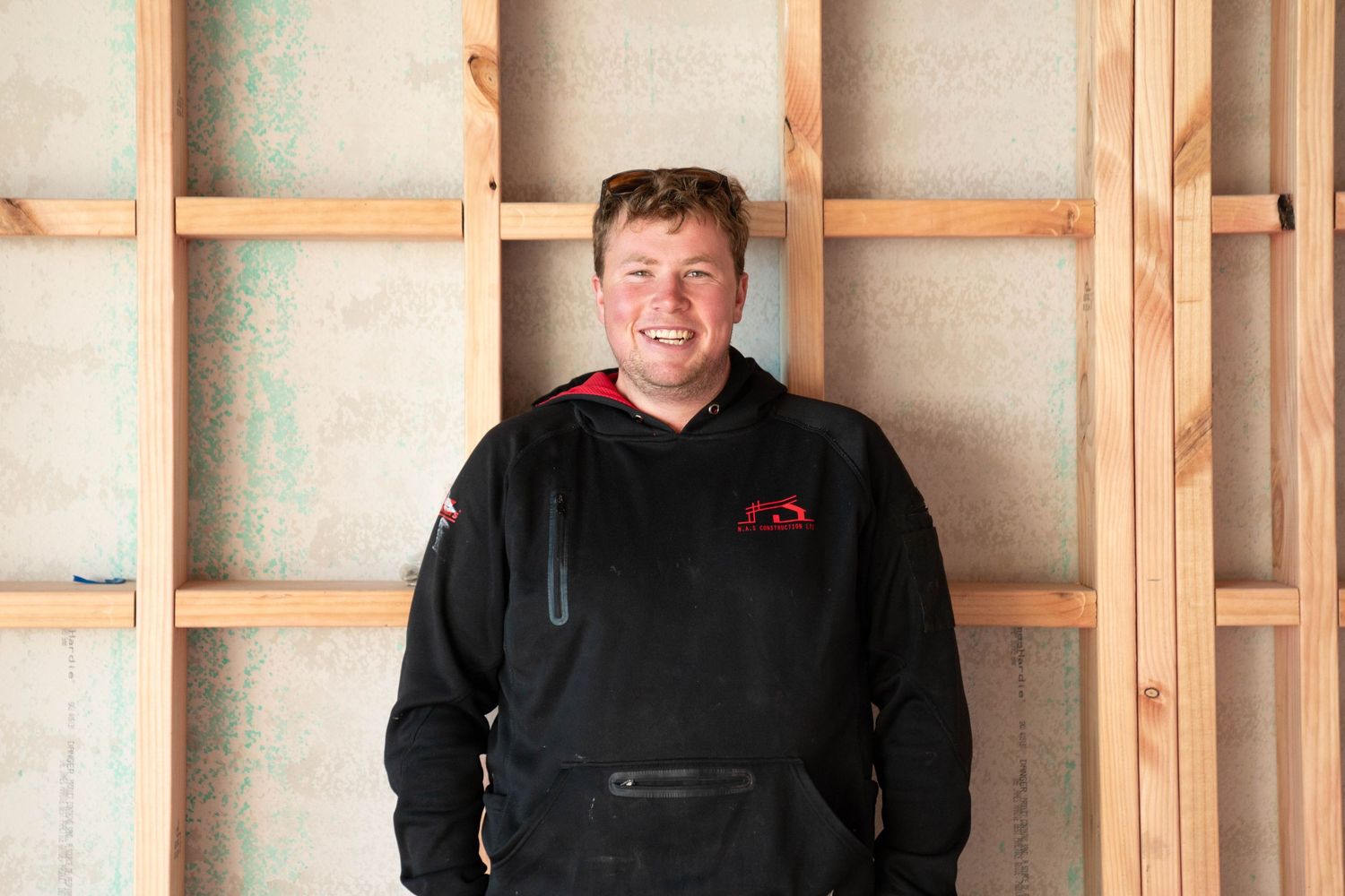 Professional photos showing construction workers smiling while working inside an unfinished building.