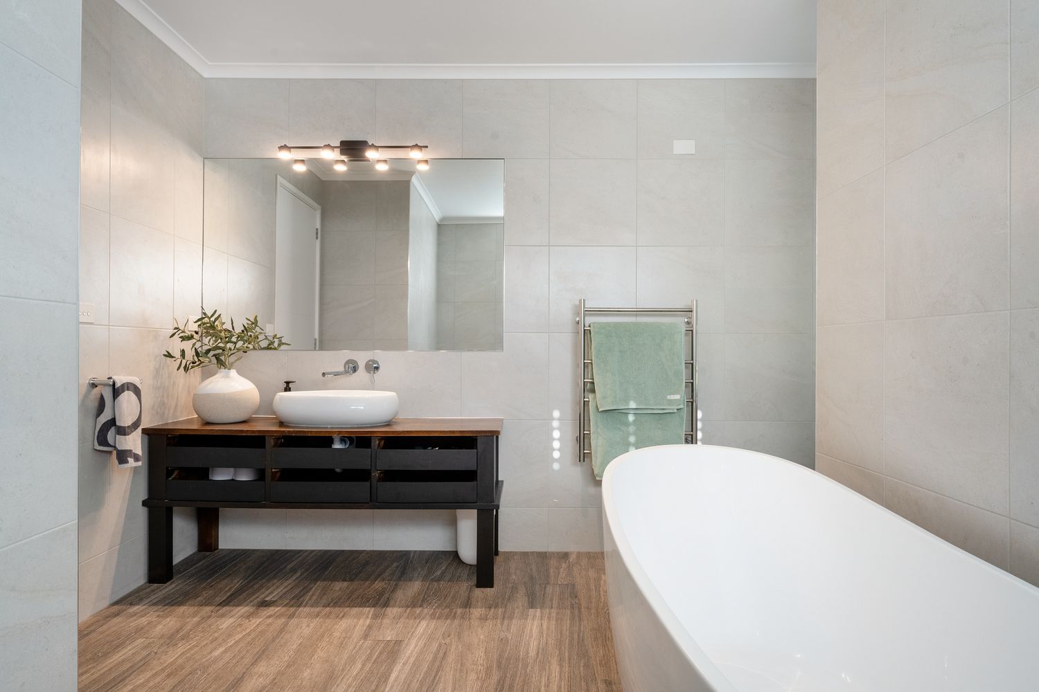 Sleek bathroom featuring freestanding tub and wooden vanity with vessel sink.