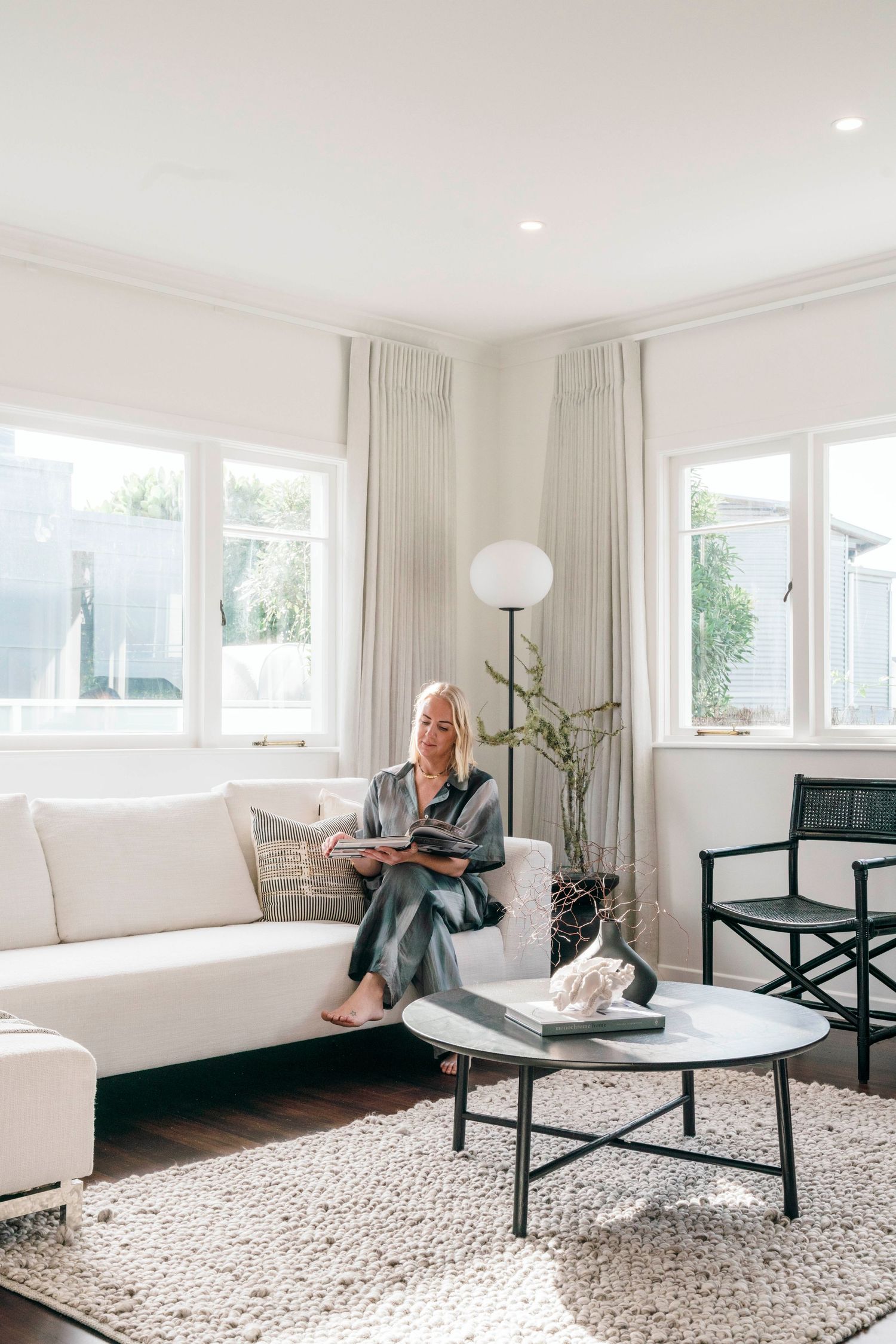 Minimalist living room with white couch and round coffee table on textured area rug.