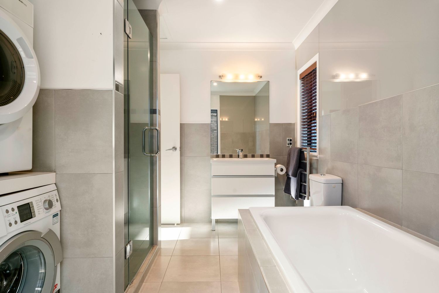 Minimalist bathroom interior with white walls, modern fixtures and large tile flooring.
