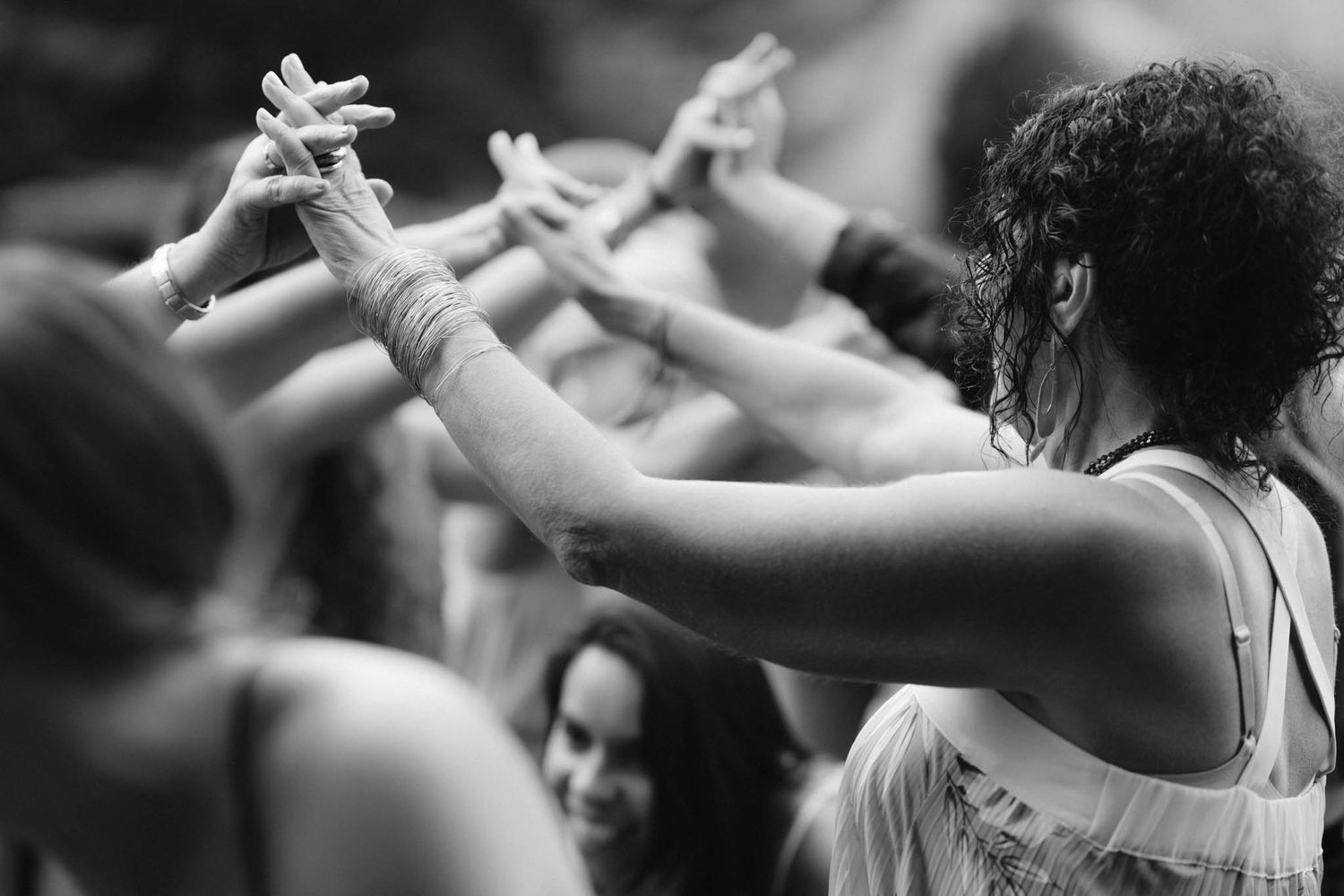 People dance in unison with raised arms during a synchronized group performance or dance class.