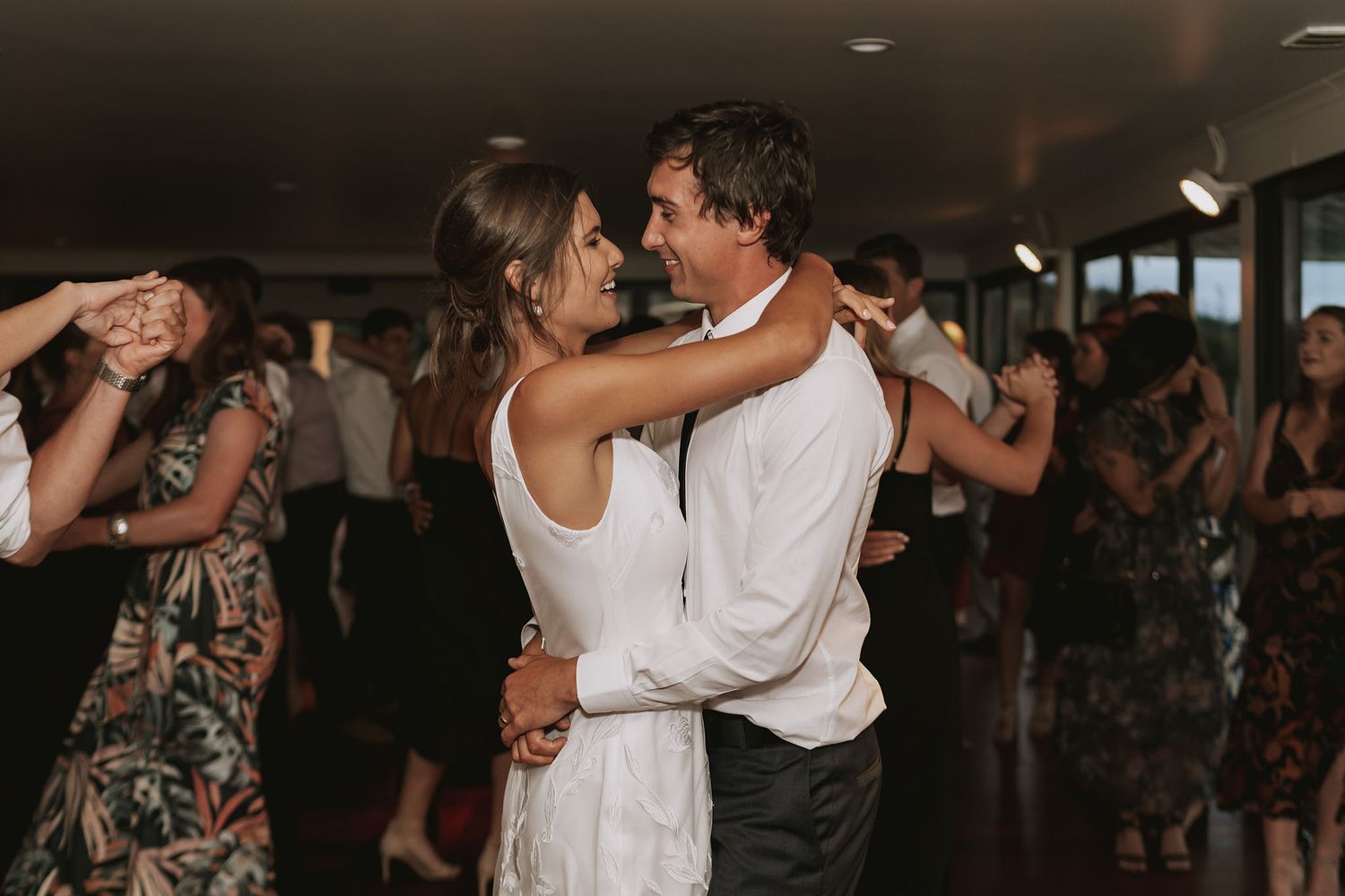 People dancing intimately together at a dimly lit reception venue.