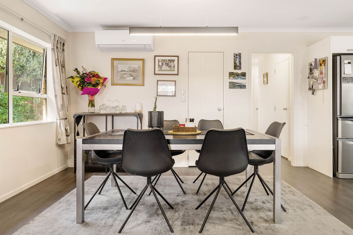 Contemporary dining area with modern black chairs and table set against white walls and natural lighting.