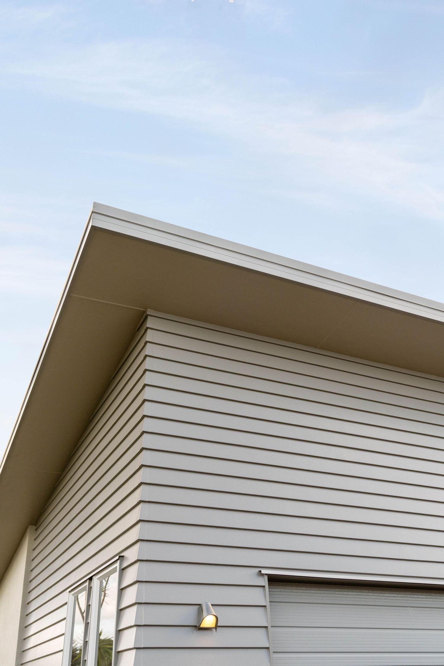 Angular white siding panels on the exterior of a modern residential building create a geometric pattern against the sky.