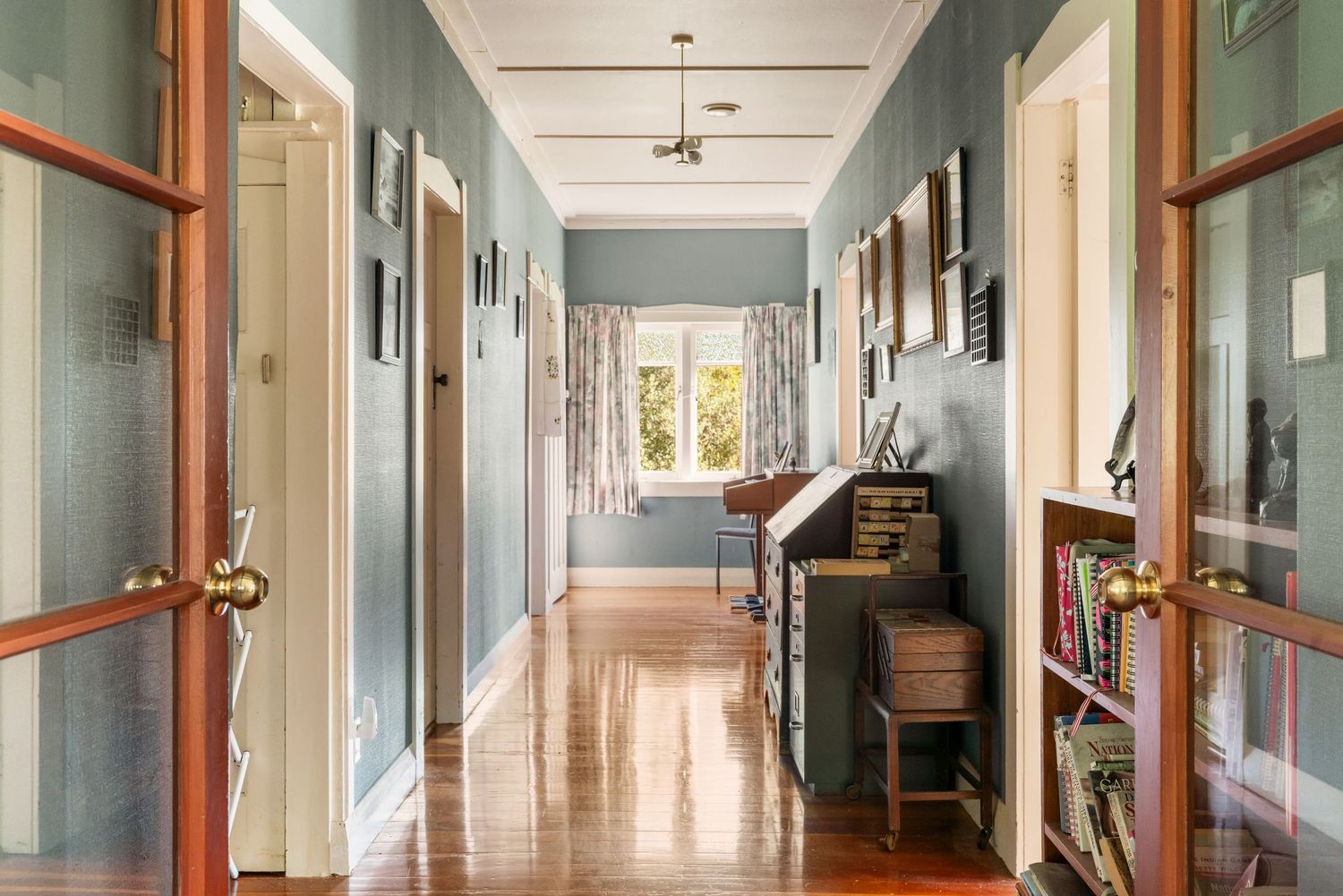Long hallway interior with light blue walls, wooden trim and polished hardwood floors.