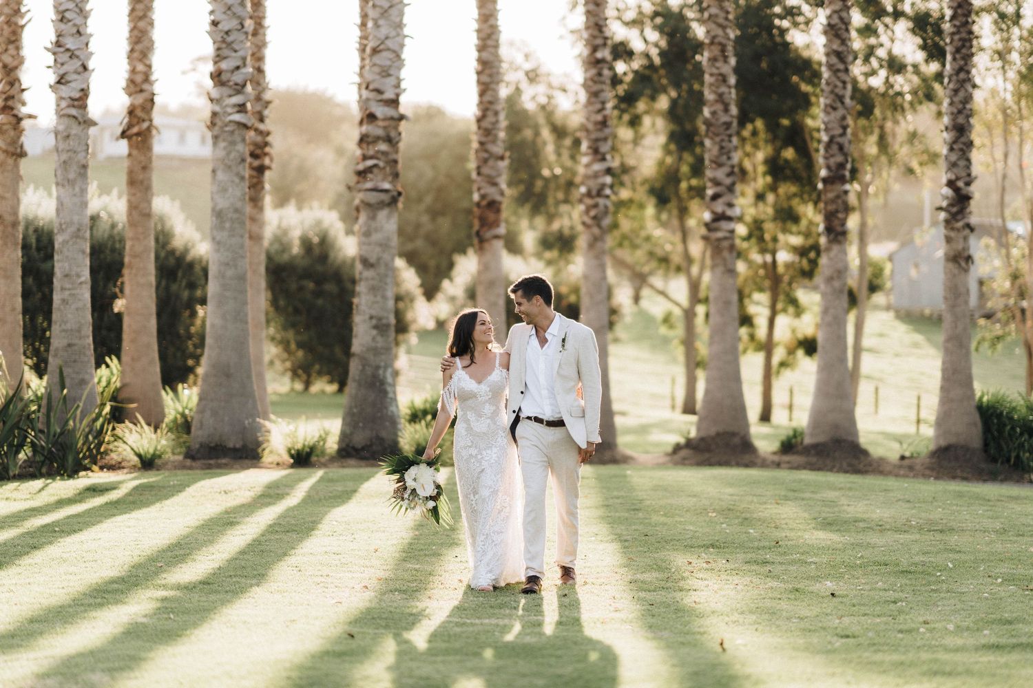 A romantic sunset photo between palm trees on a manicured lawn.