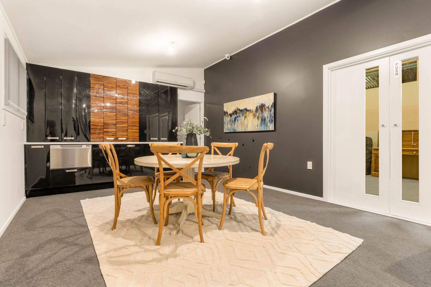 Contemporary dining area with wooden table, grey accent wall, and black brick feature wall.