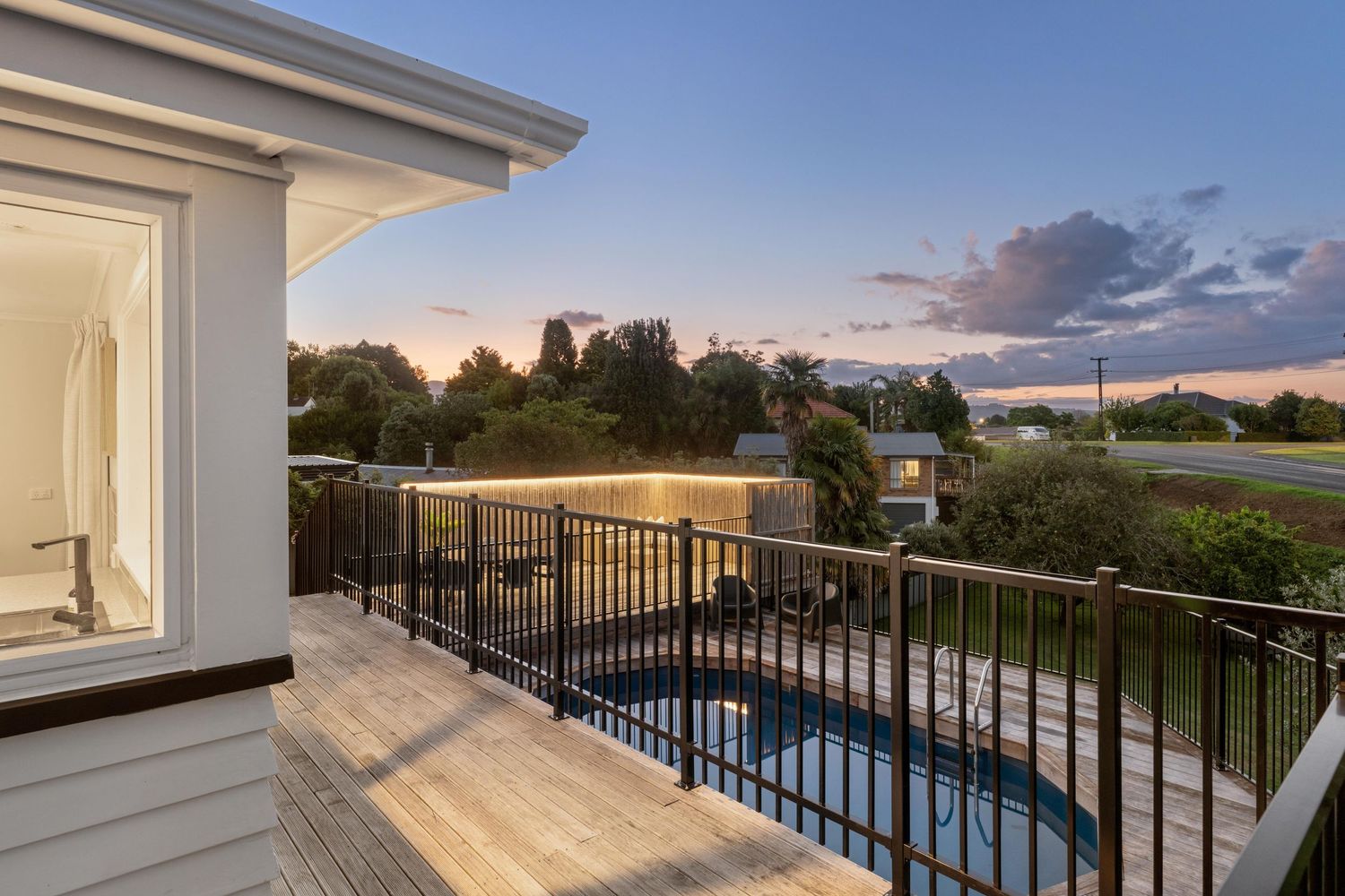 Sunset view from deck showing pool and neighborhood landscape in golden light.