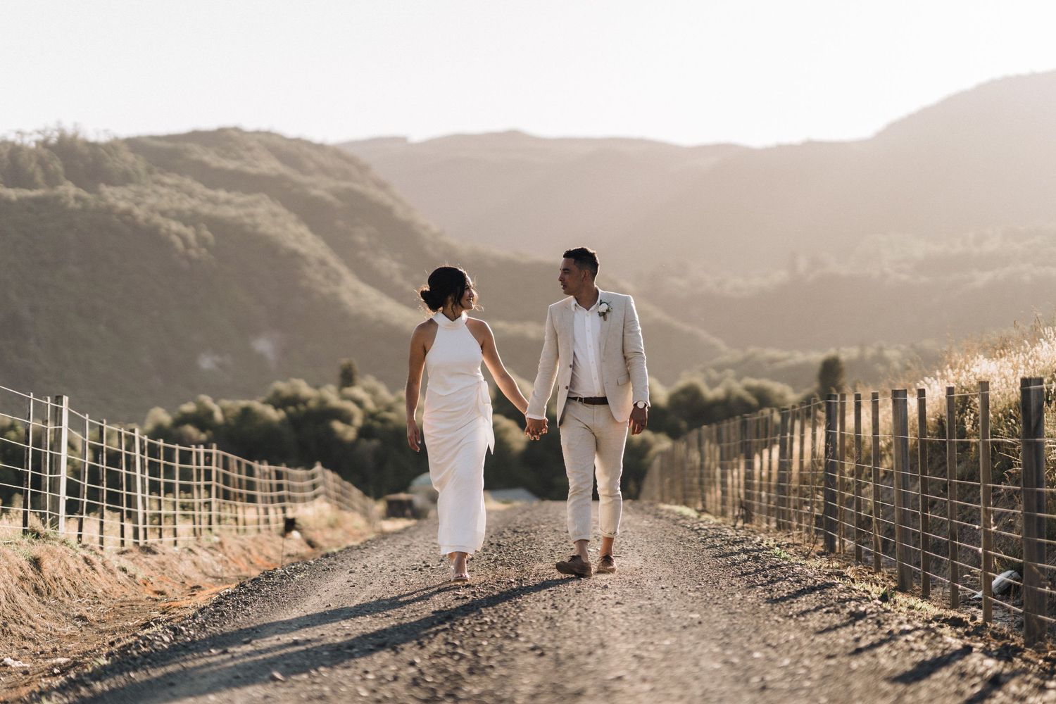 Couple walking hand in hand on mountain path with scenic valley views.