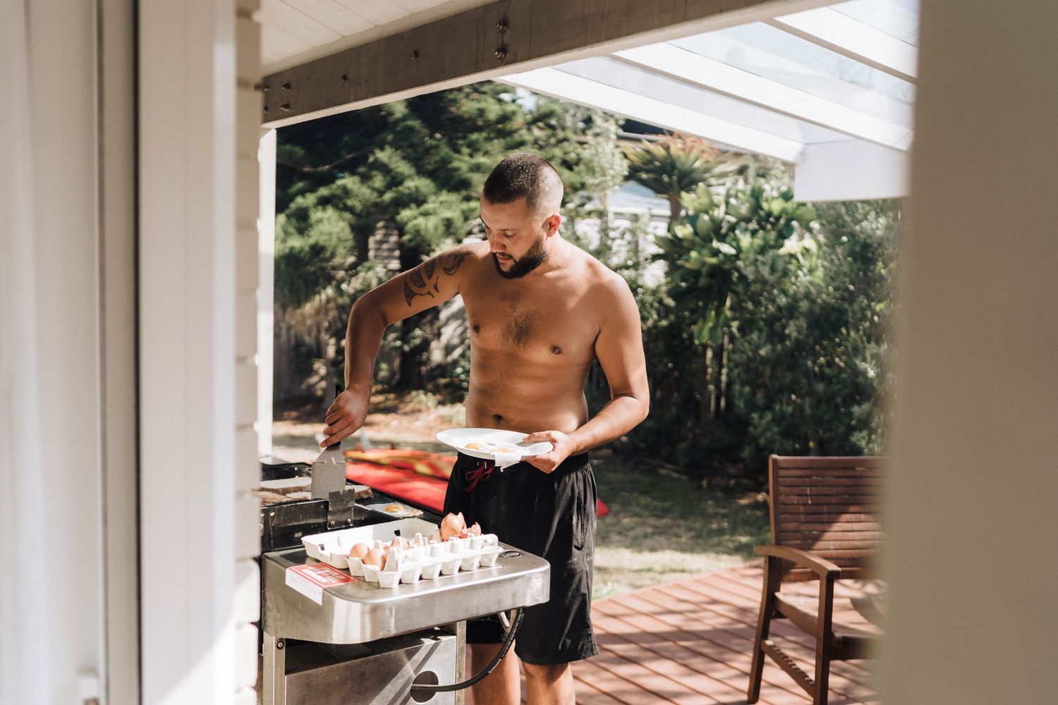 Person grilling food outdoors on a barbecue in a backyard patio setting.