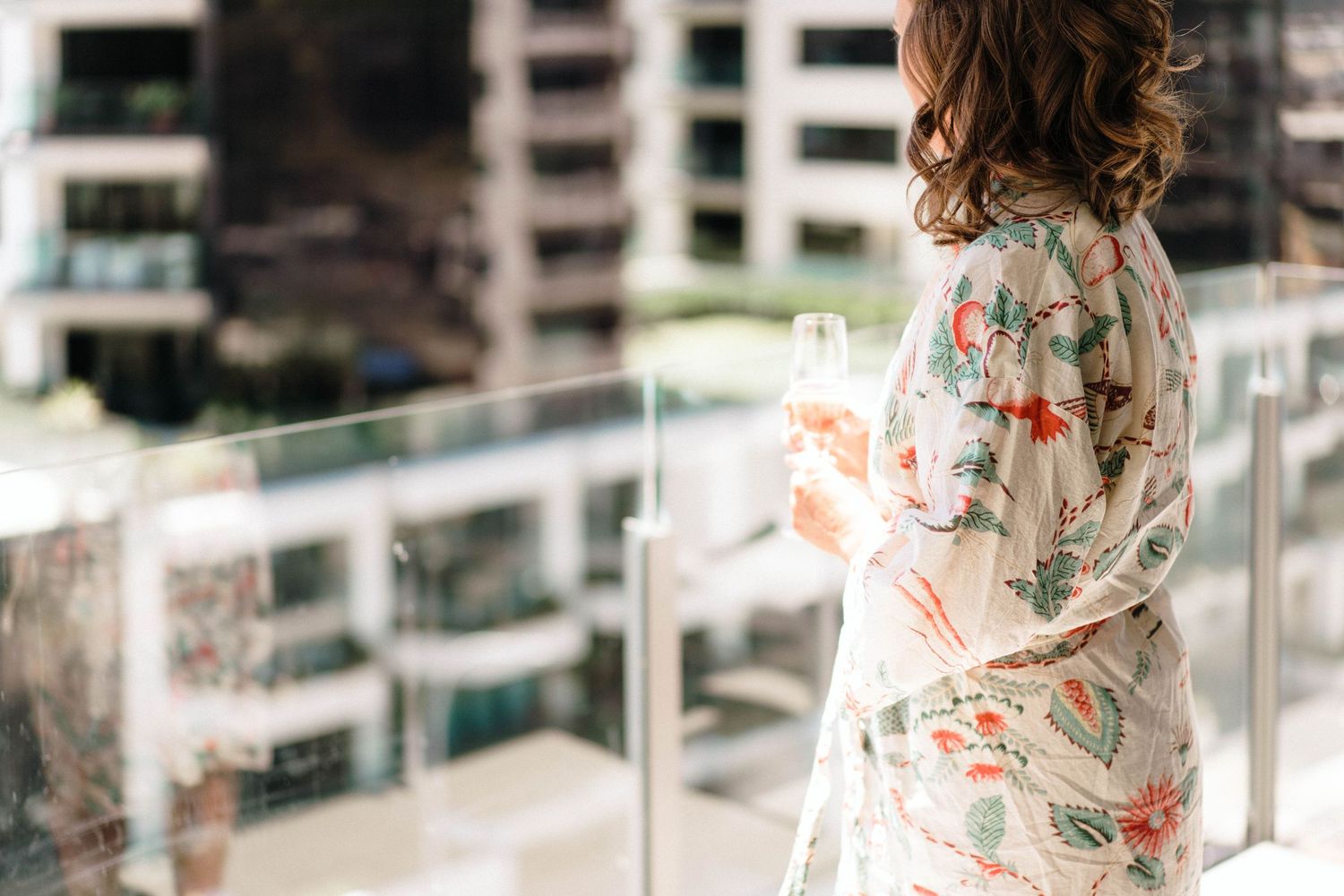 Woman wearing floral maxi dress with ruffled sleeves poses in bright multi-level indoor setting.