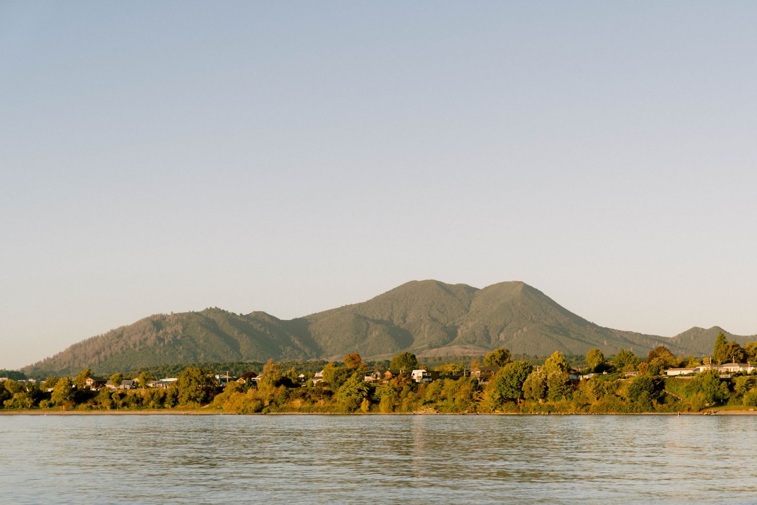 Scenic panoramic view of mountains and waterfront with lush greenery in the background.