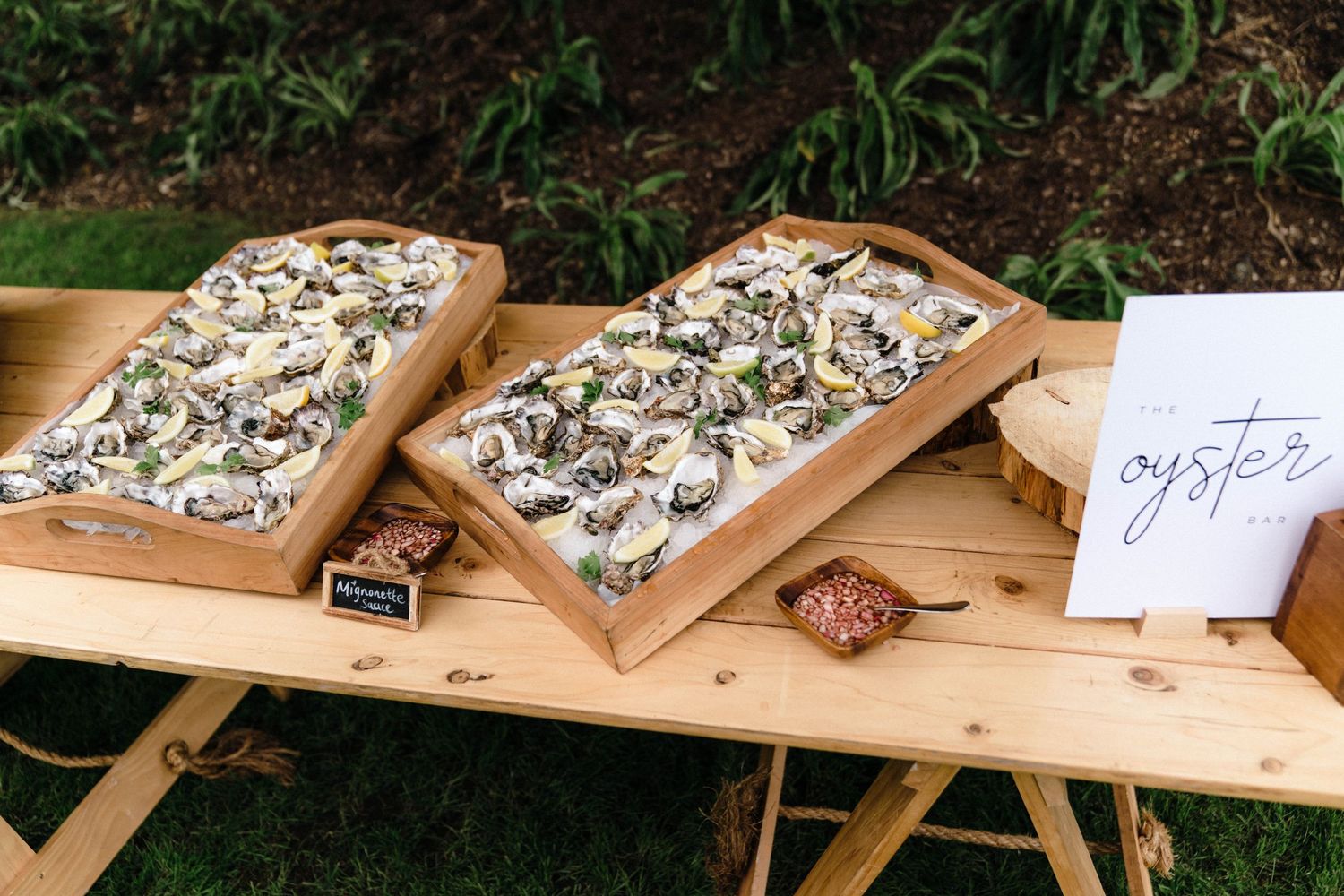 Fresh oysters displayed on wooden serving boards at an outdoor event.