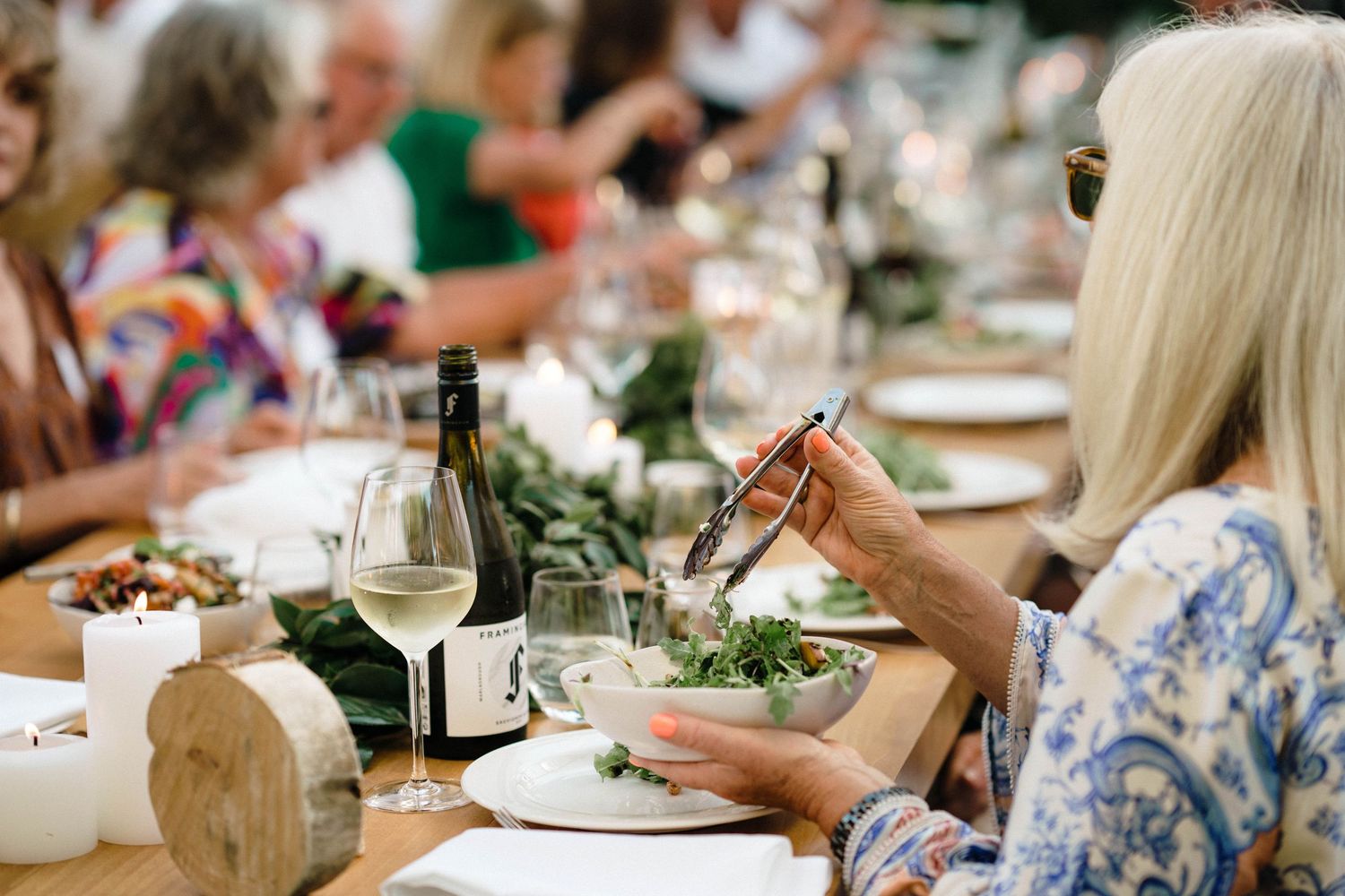 Guests dining at long tables during an elegant outdoor wedding reception.