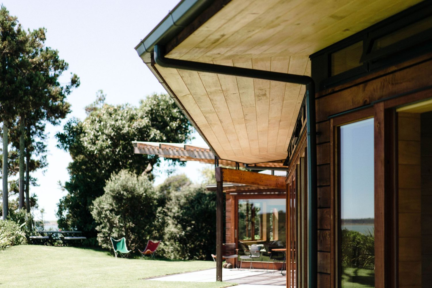 Modern wooden architectural exterior with angled roof lines and large windows overlooking a natural landscape.