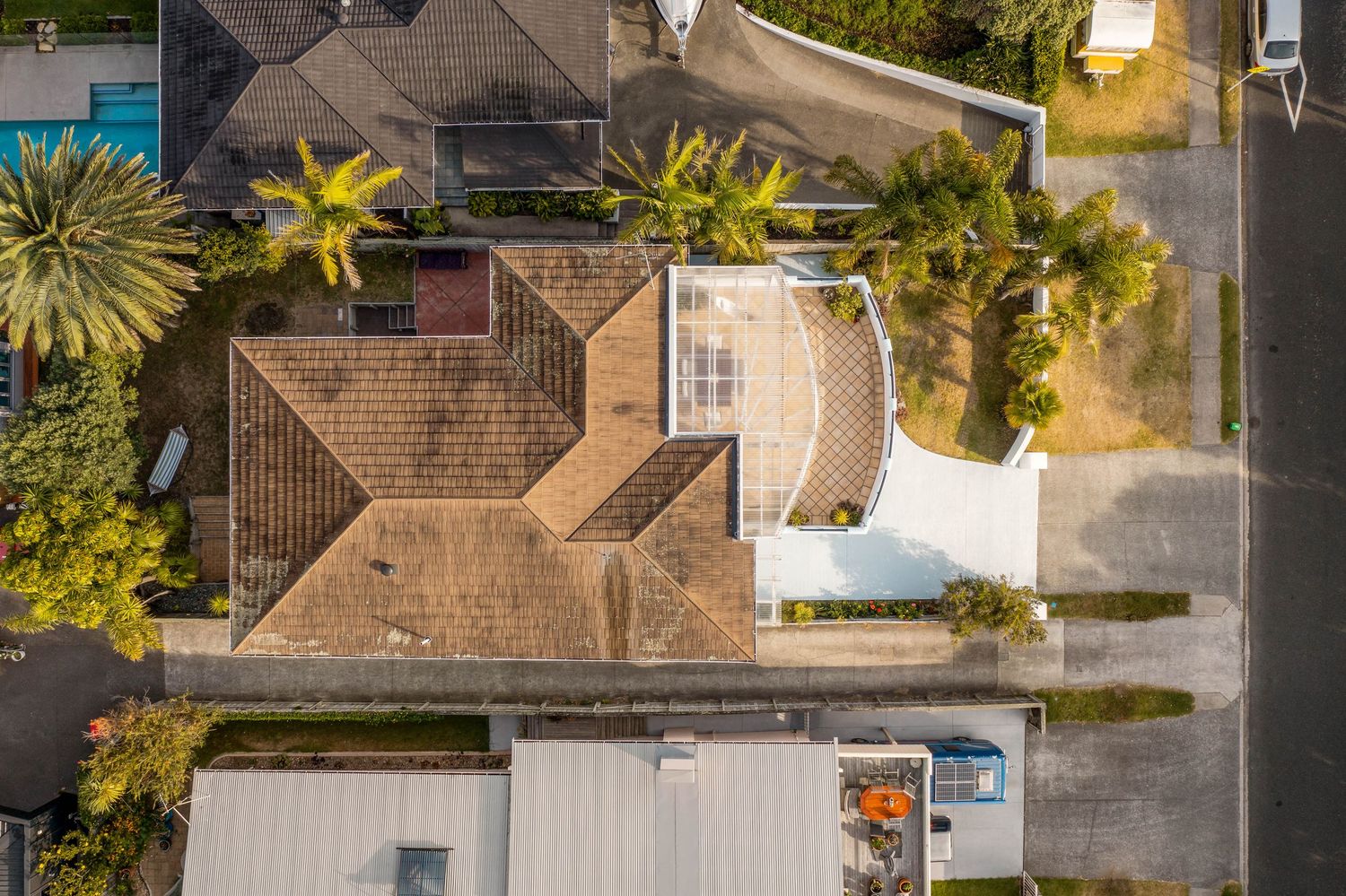 Bird's eye view of residential homes with terracotta roofs and lush gardens in a suburban setting.