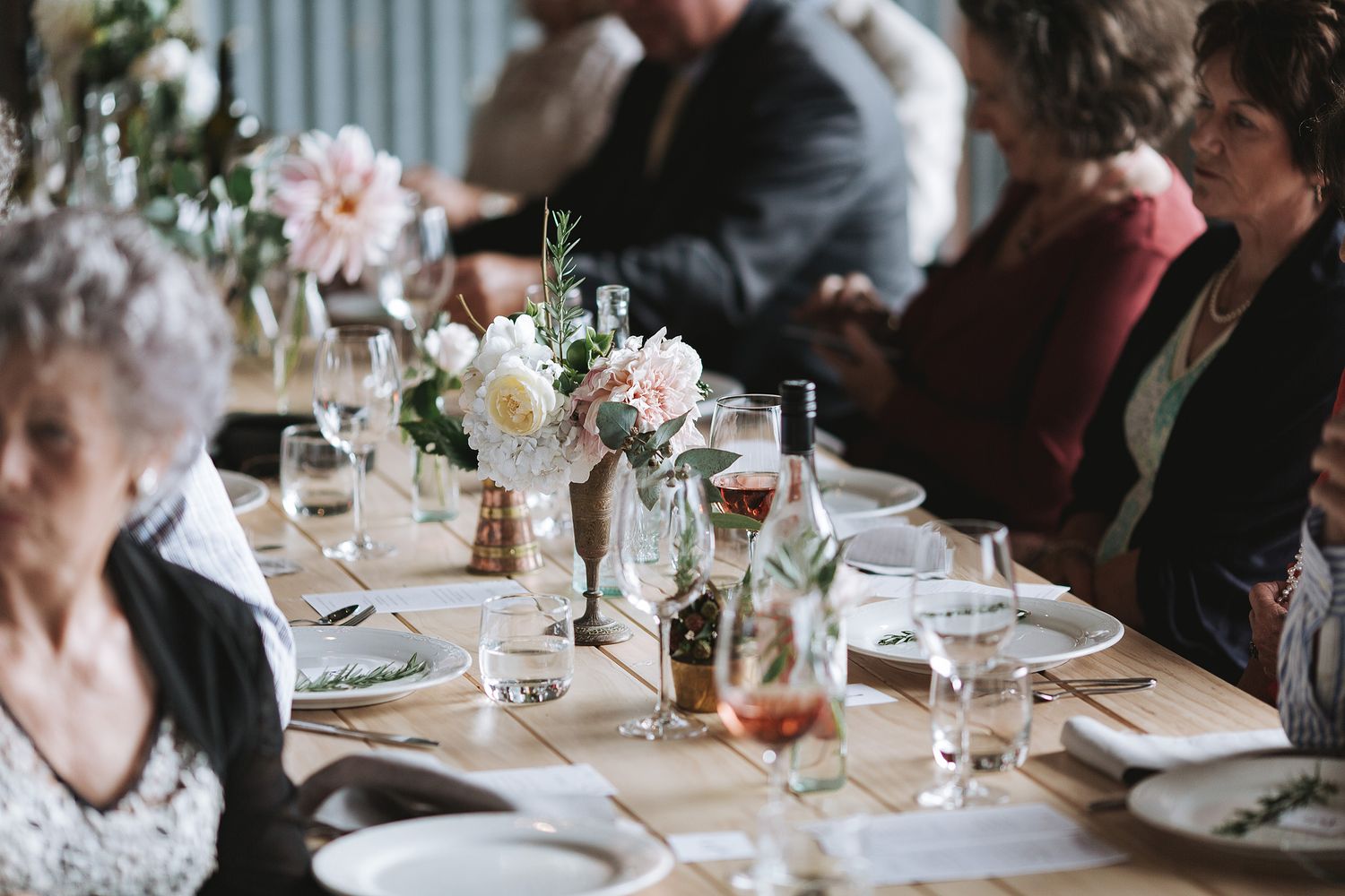 Wedding reception tables set with elegant place settings, flowers and glassware in a romantic candlelit atmosphere.