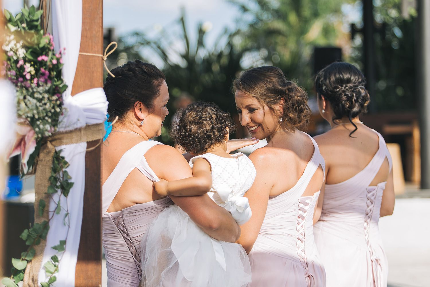 Bridesmaids in matching dresses share an emotional embrace during a wedding celebration.