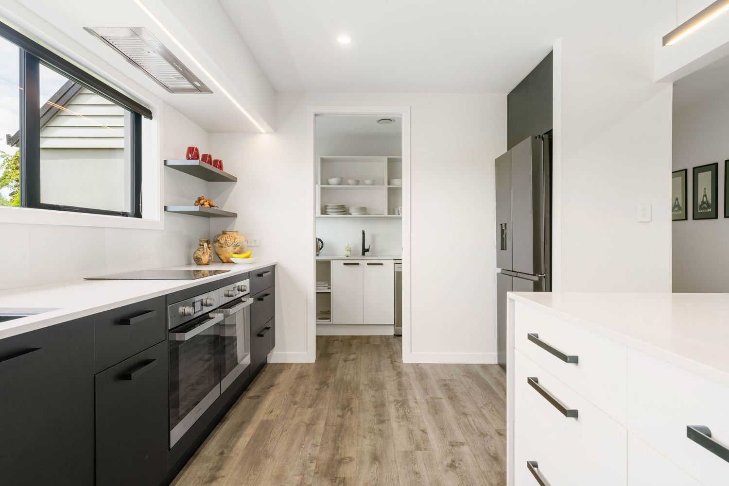 Modern minimalist open concept apartment interior with white walls, gray floors and sleek black kitchen cabinetry.