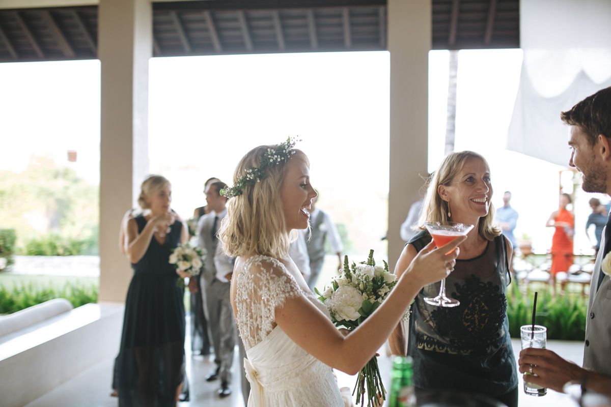 Wedding reception party with guests mingling under covered outdoor pavilion near the beach.