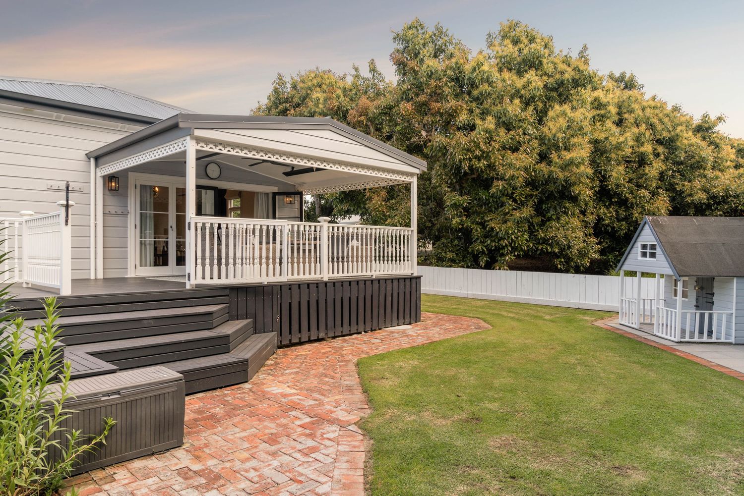 Outdoor patio area with brick pavers and white railing extending from the main house.