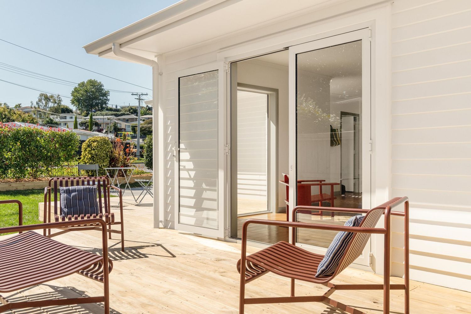 A series of wooden porch railings and outdoor seating areas with white siding and covered overhangs in a residential setting.